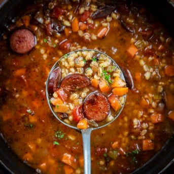 Ladle full of Kielbasa Barley Soup held above the pot.