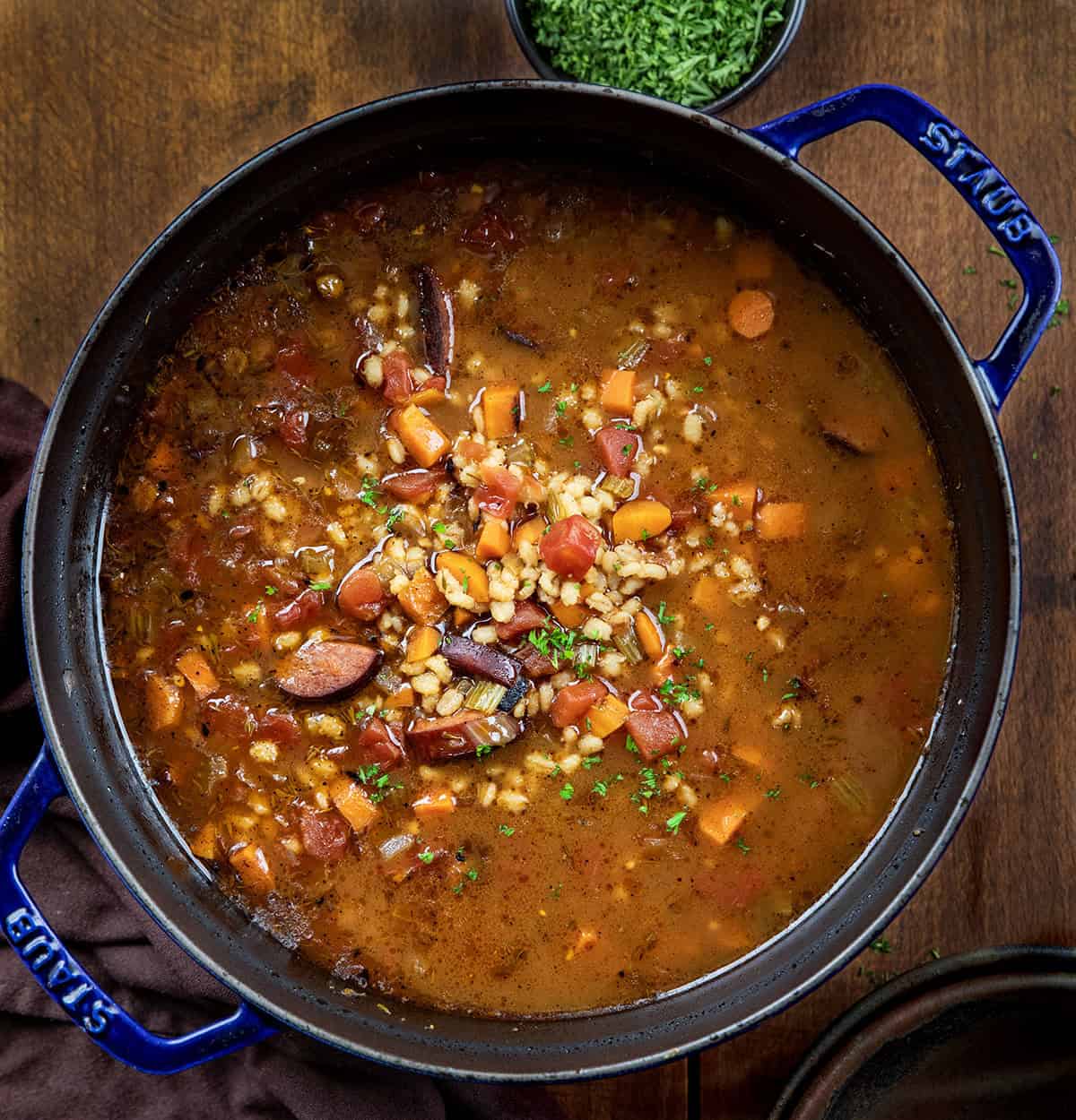 Pot of Kielbasa Barley Soup on a wooden table from overhead.
