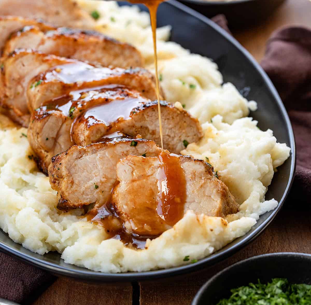 Drizzling sauce over Maple Dijon Pork Tenderloin slices.