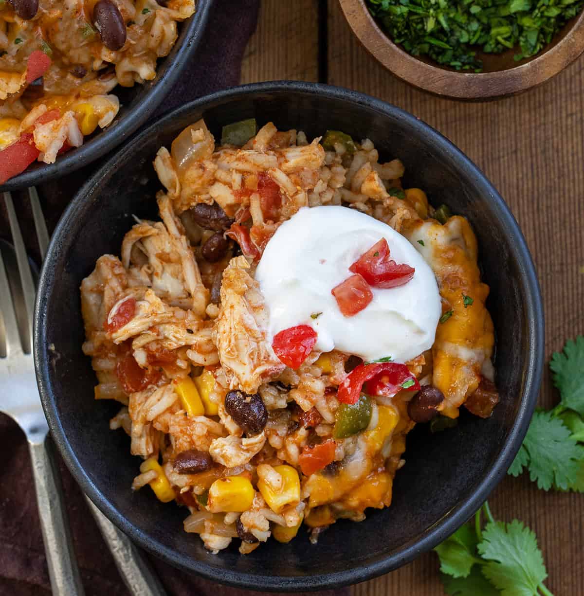 Black plates of Southwest Chicken Rice Skillet on a wooden table from overhead.
