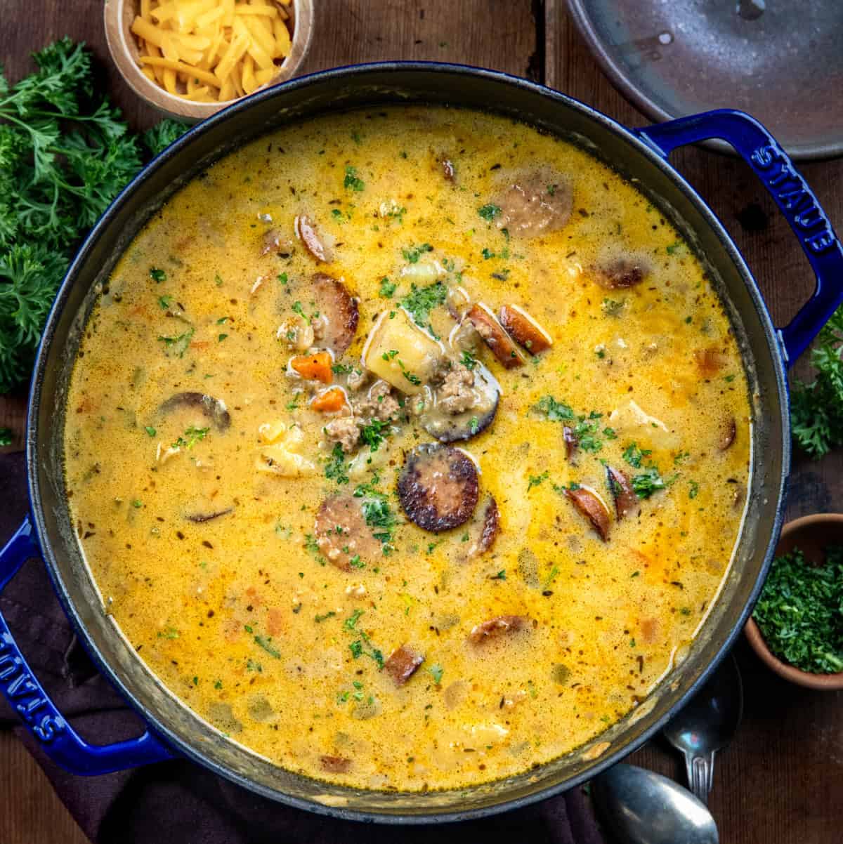 Pot of Spicy Cajun Sausage Potato Soup on a wooden table from overhead.