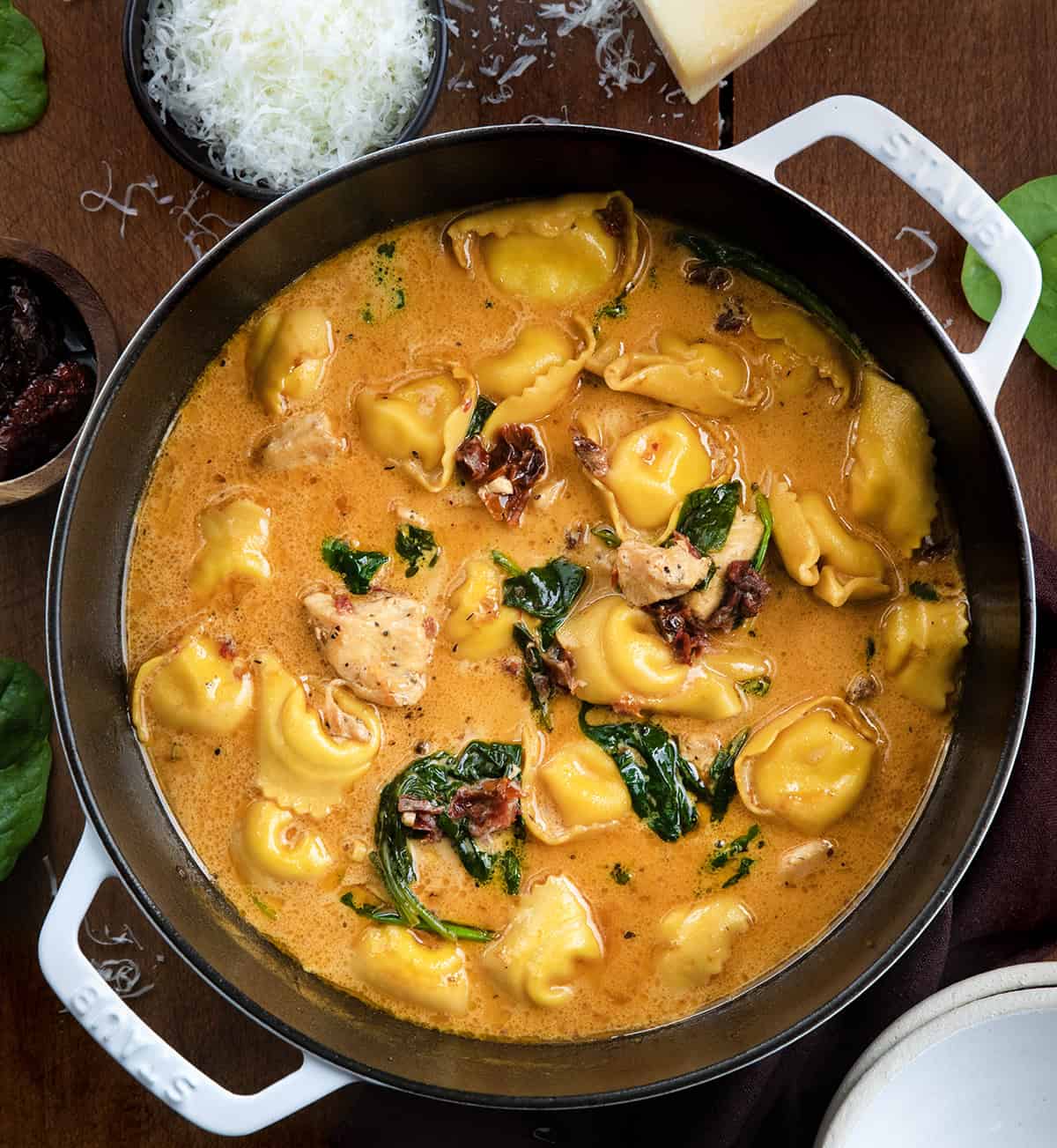 Pot of Tuscan Chicken Tortellini Soup on a wooden table from overhead.