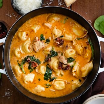 Pot of Tuscan Chicken Tortellini Soup on a wooden table from overhead.