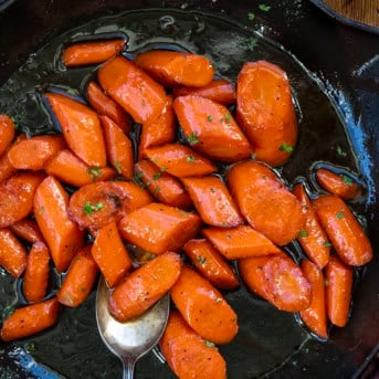 Skillet of Candied Carrots with a spoon resting in the pan from overhead.