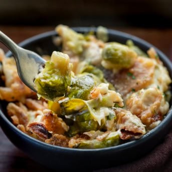 Forkful of Cheesy Brussels Sprout Casserole being held above a black bowl.