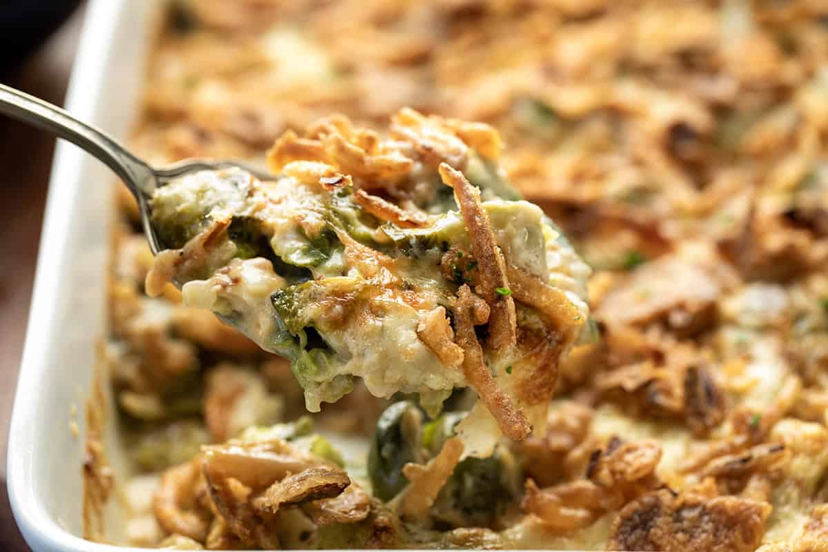 This Cheesy Brussels Sprout Casserole takes tender Brussels sprouts and coats them in a rich, creamy cheese sauce before baking them under a layer of golden, crispy onions. It’s warm, comforting, and indulgent in the best way... an easy side dish that turns a simple vegetable into something everyone will want seconds of! Scoop of Cheesy Brussels Sprout Casserole being lifted from the dish.