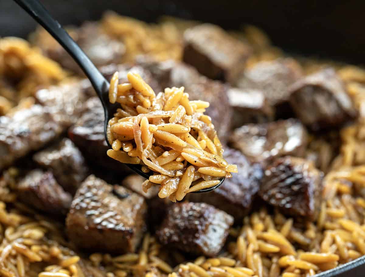 Steak and Caramelized Onion Orzo gives you the best of both worlds. Tender seared steak bites meet deeply sweet caramelized onions, all nestled in creamy Parmesan orzo that feels special enough for company but easy enough for any weeknight! Close up of Caramelized Onion Orzo.