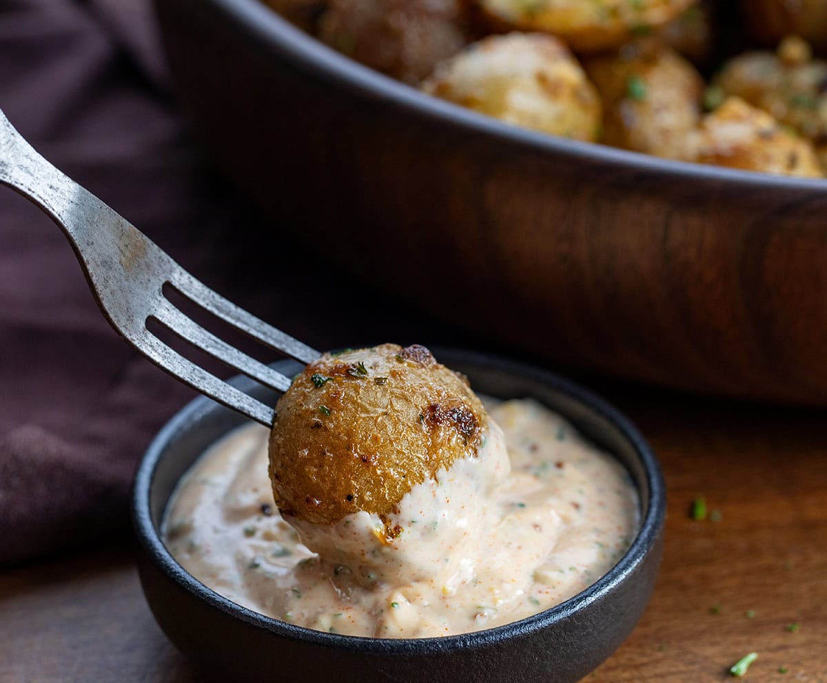 Try Cowboy Mayo Roasted Potatoes for a flavorful side dish! Simple, delicious, and perfect for any meal or get-together! Dipping a roasted potato into cowboy mayo.