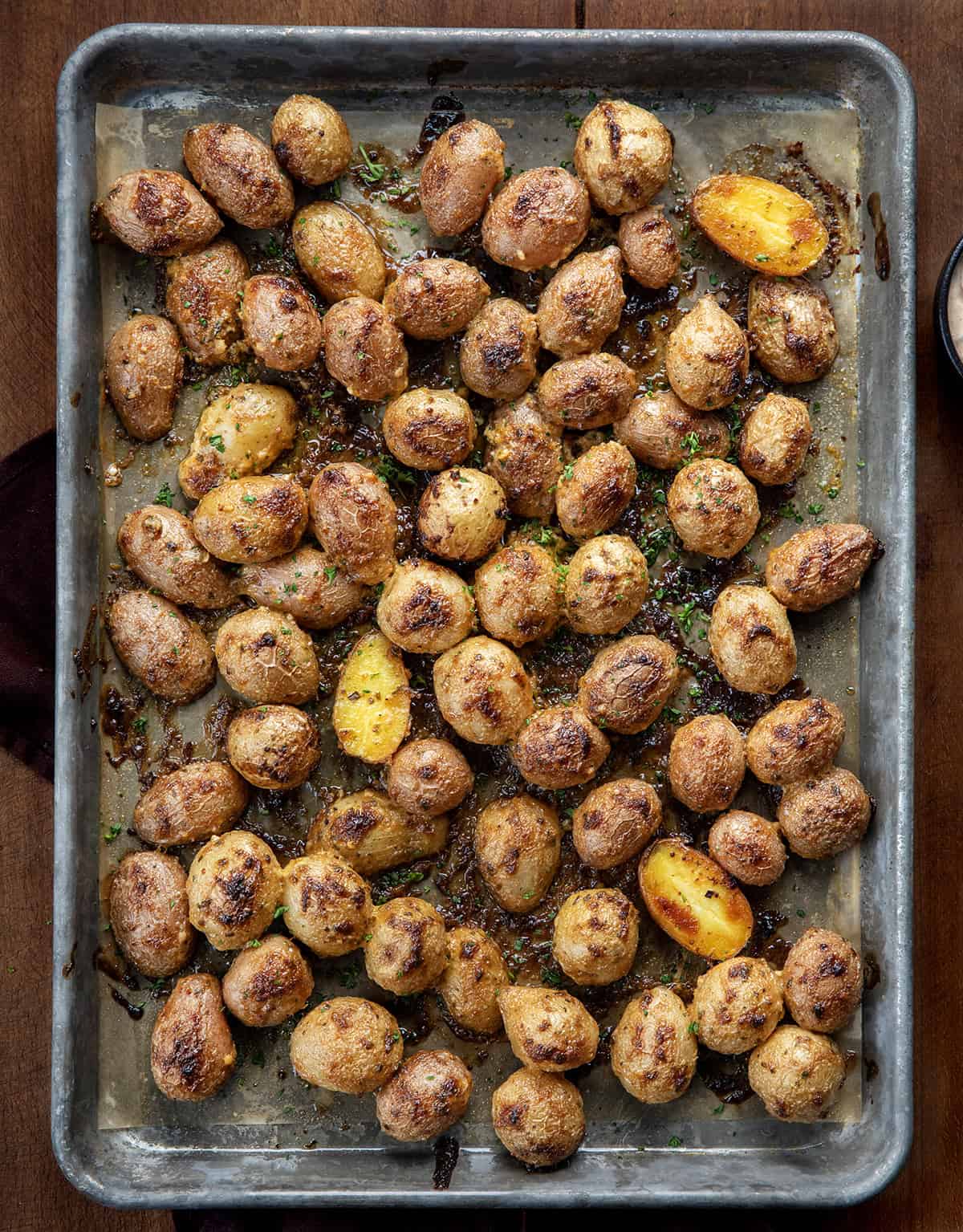 Try Cowboy Mayo Roasted Potatoes for a flavorful side dish! Simple, delicious, and perfect for any meal or get-together! Sheet pan of Cowboy Mayo Roasted Potatoes on a wooden table from overhead.