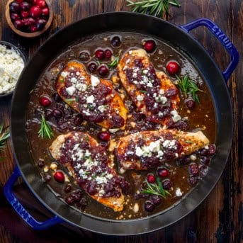Skillet of Cranberry Feta Chicken Bake on a wooden table from overhead.