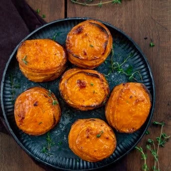 Black platter with Crispy Sweet Potato Stacks on it on a wooden table from overhead.