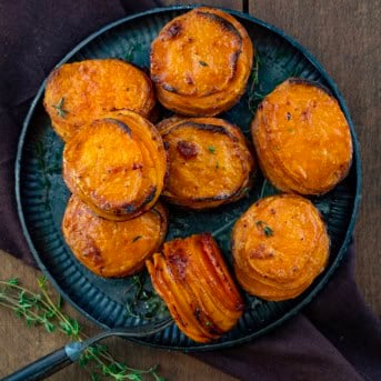 Black platter of Crispy Sweet Potato Stacks with one stack on its side with a fork in it.