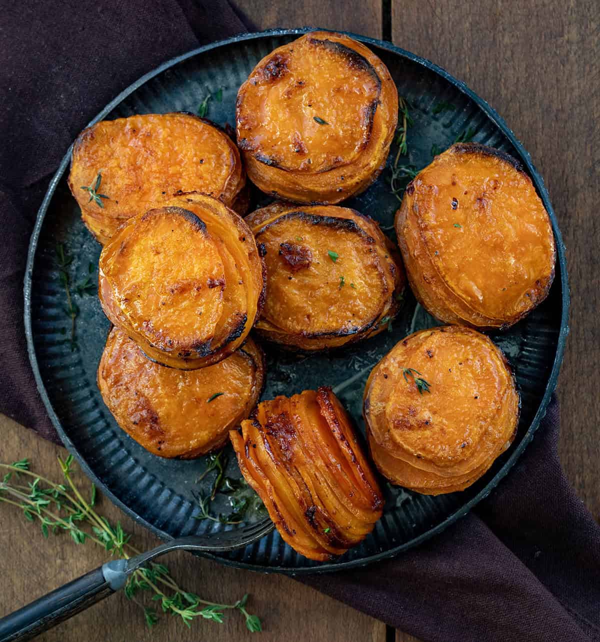 Black platter of Crispy Sweet Potato Stacks with one stack on its side with a fork in it.