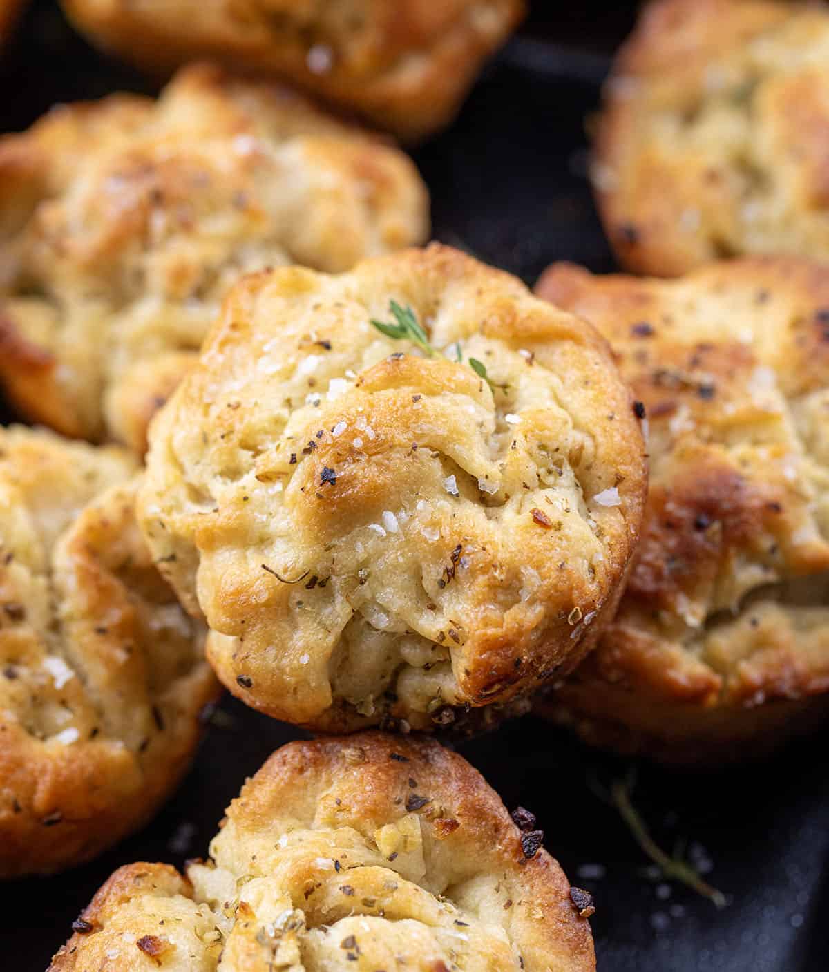 These Focaccia Muffins are crispy on the outside, soft and airy inside, and bursting with garlic, olive oil, and herbs. Close up of Focaccia Muffins.