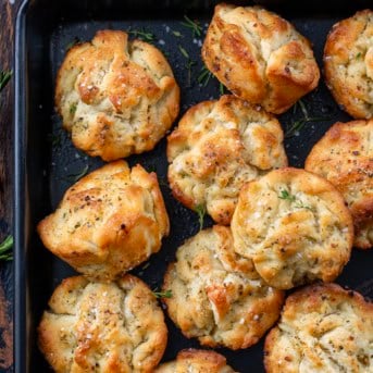 Focaccia Muffins in a black pan on a wooden table from overhead.