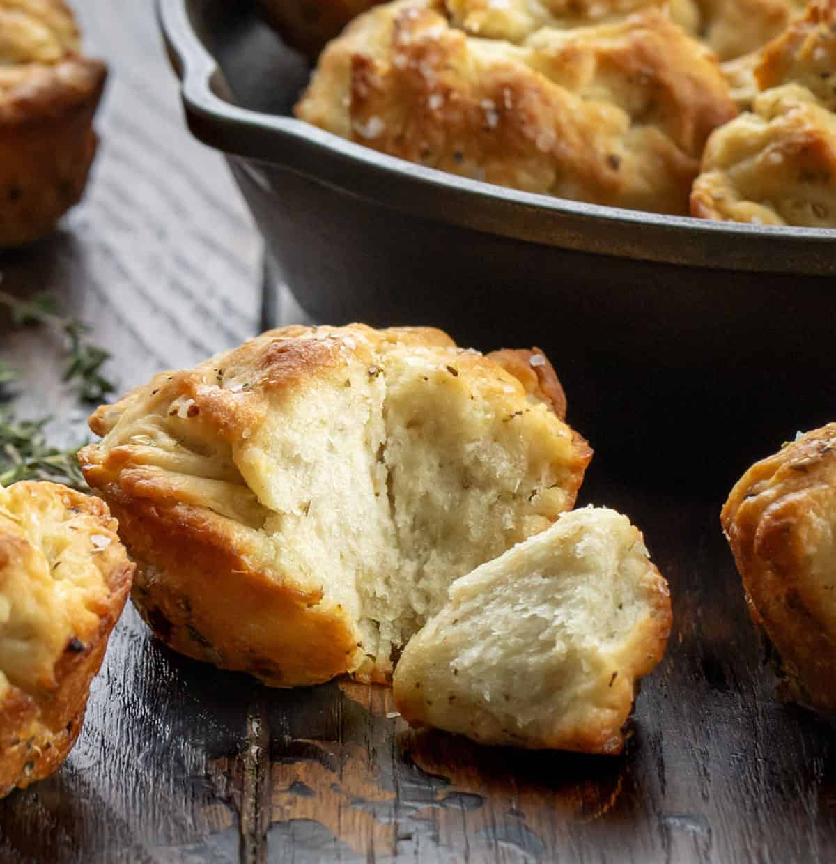 These Focaccia Muffins are crispy on the outside, soft and airy inside, and bursting with garlic, olive oil, and herbs. Torn up Focaccia Muffin on a wooden table.