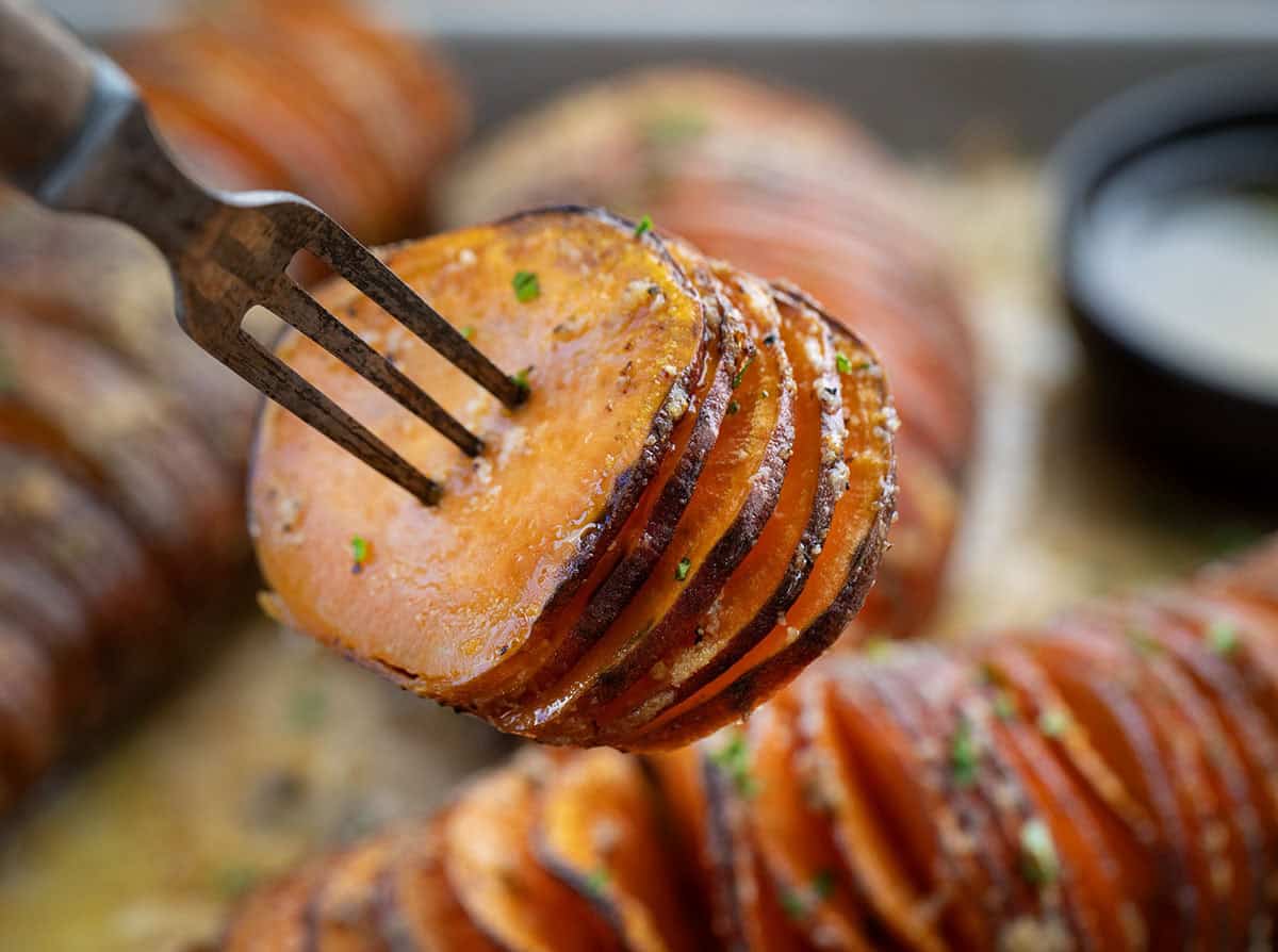 Crispy on the edges and buttery in the center, these Hasselback Sweet Potatoes are an easy side dish that looks extra special on the table! Hasselback Sweet Potato piece on a fork.