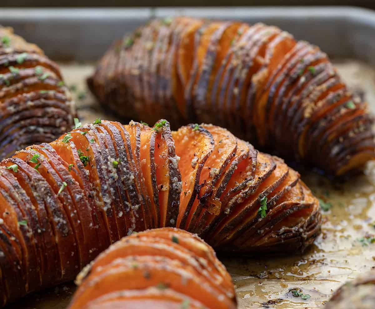Crispy on the edges and buttery in the center, these Hasselback Sweet Potatoes are an easy side dish that looks extra special on the table! Close up of Hasselback Sweet Potatoes on a sheet pan.