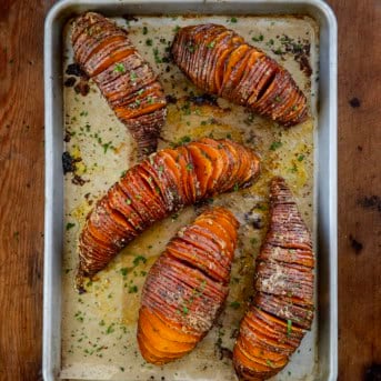 Hasselback Sweet Potatoes on a sheet pan on a wooden table from overhead.