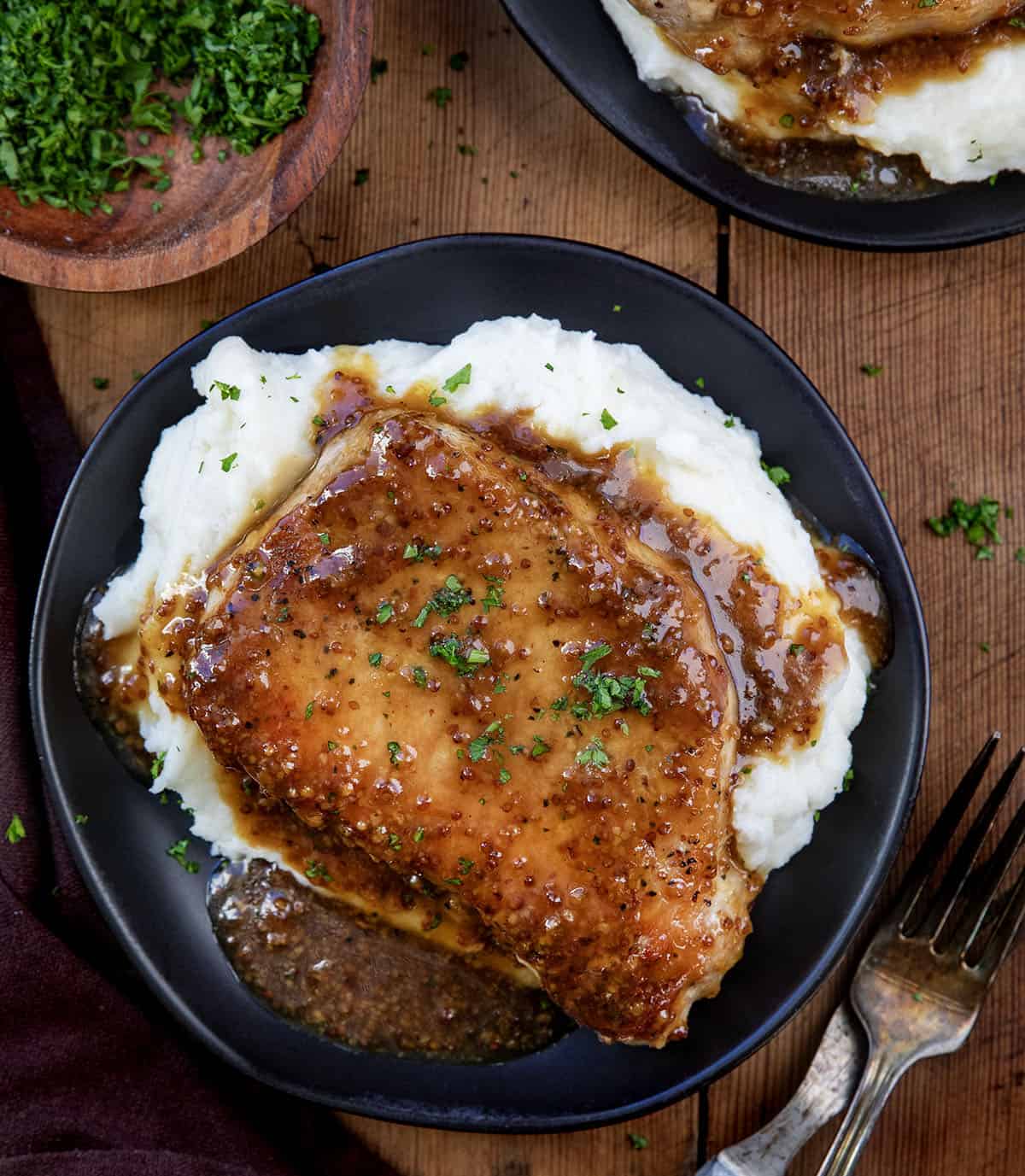Honey Mustard Pork Chops on black plates on a wooden table.
