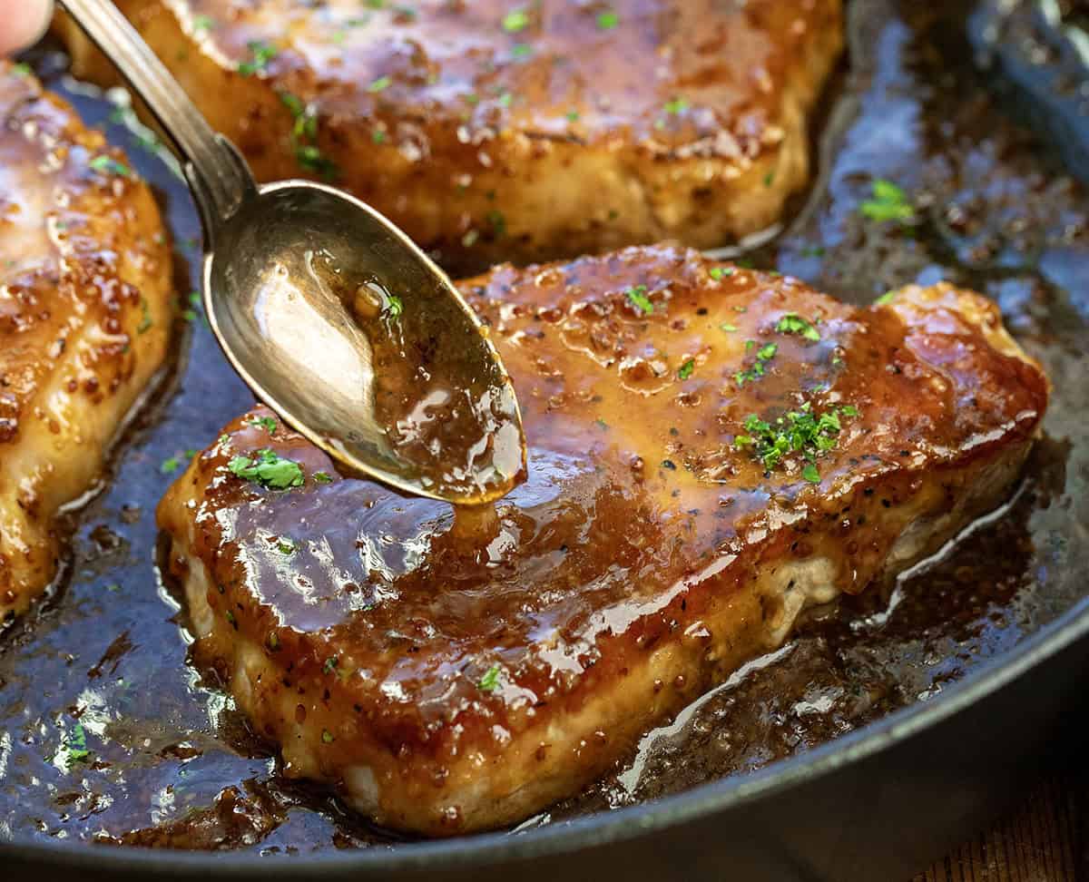 Spooning glaze over Honey Mustard Pork Chops.