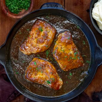 Honey Mustard Pork Chops in a black skillet on a wooden table.
