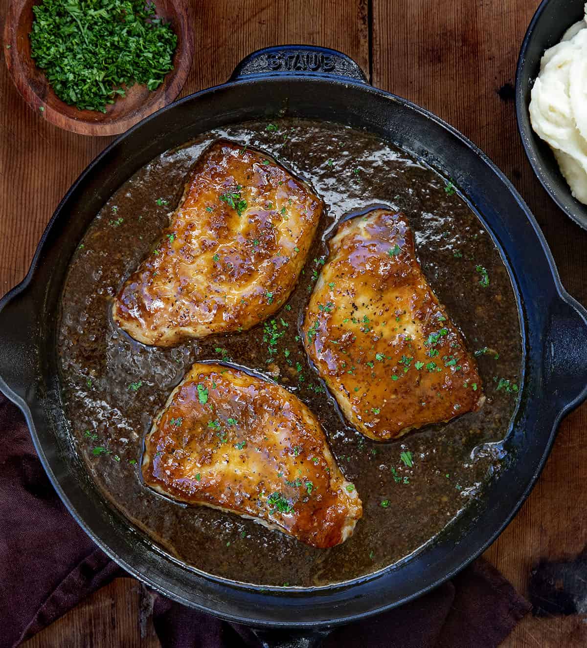 Honey Mustard Pork Chops in a black skillet on a wooden table. 