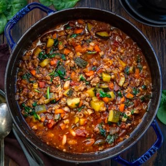 Pot of Minestrone Soup with Sausage on a wooden table from overhead.