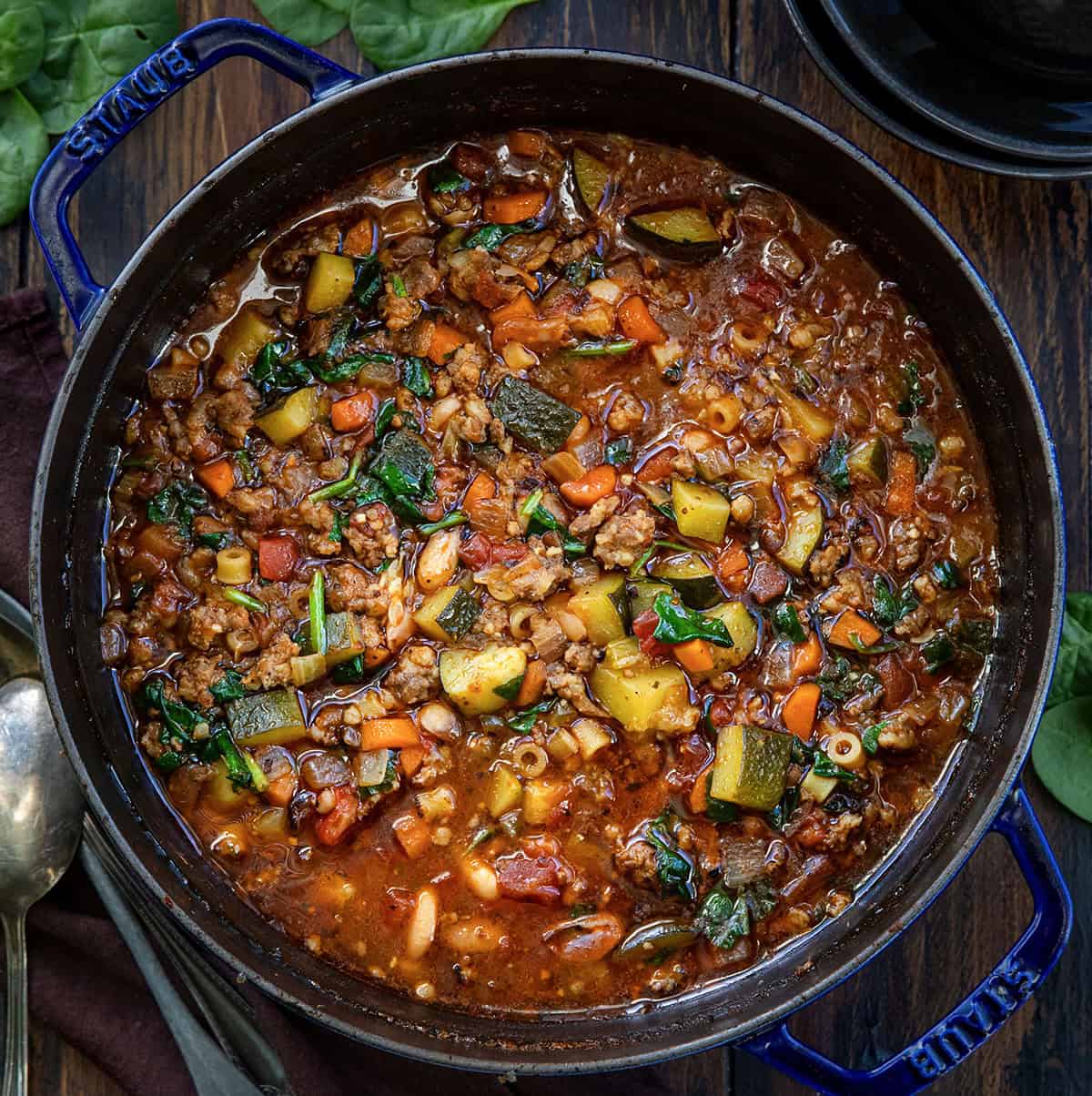 Enjoy a warm bowl of Minestrone Soup with Sausage, packed with vegetables and flavors for a cozy meal in under an hour! Pot of Minestrone Soup with Sausage on a wooden table from overhead.