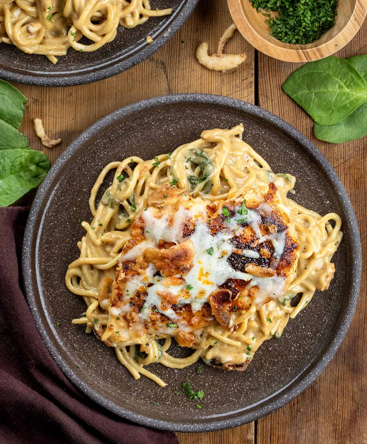 Plates of Monterey Chicken Spaghetti on a wooden table from overhead.