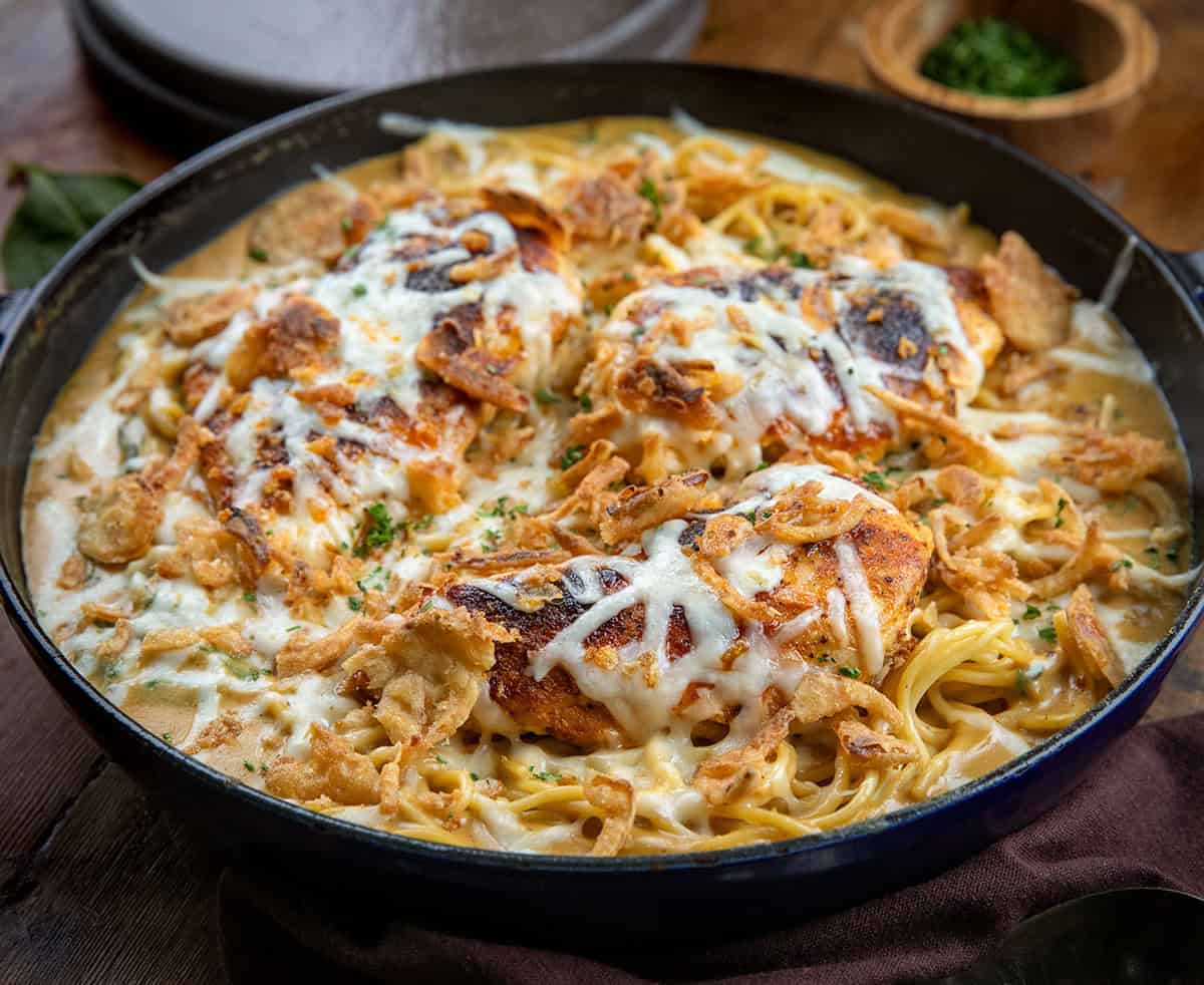 Close up of a skillet of Monterey Chicken Spaghetti on a wooden table.