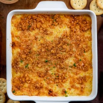 Scalloped Corn in a white baking dish on a wooden table with Ritz crackers.