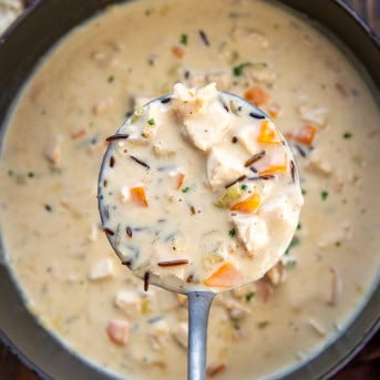 Ladle full of Turkey Wild Rice Soup being held above the pot.