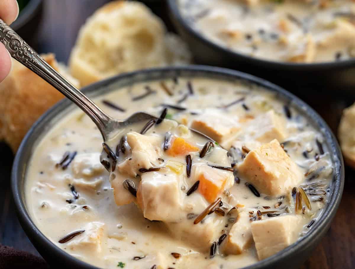 Spoonful of Turkey Wild Rice Soup being held above the bowl.