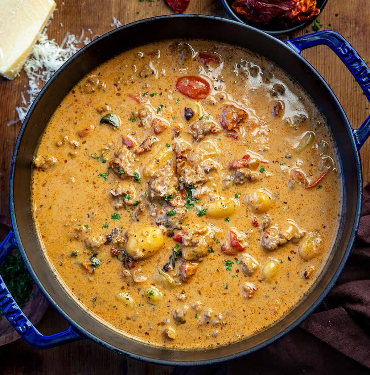 Pot of Tuscan Sausage Gnocchi Soup on a wooden table from overhead.