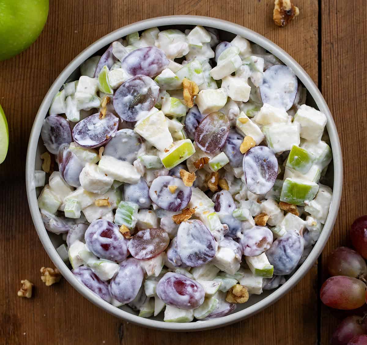 Waldorf Salad on a wooden table with green apples and red grapes from overhead.