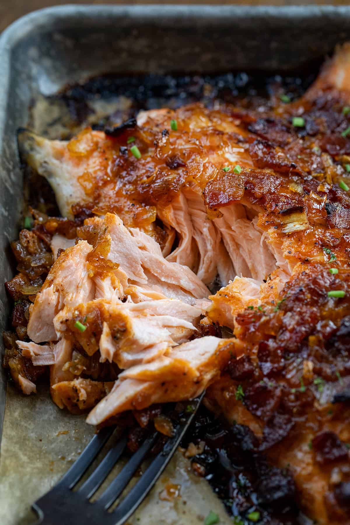 This Bacon Jam Salmon is an easy, show-stopping dinner made with my homemade onion bacon jam, which you will LOVE. The sweet, savory glaze adds rich flavor to tender, flaky salmon, perfect for weeknight dinners or special occasions! Close up of flakey Bacon Jam Salmon.