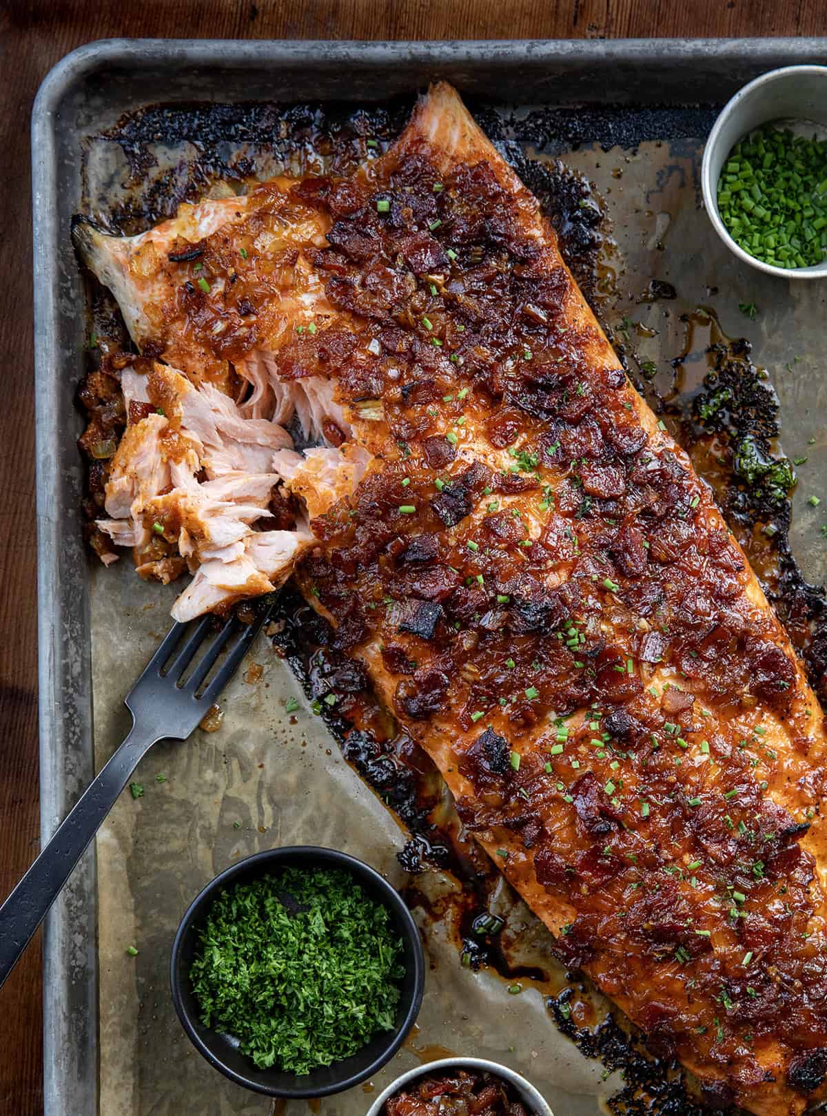 This Bacon Jam Salmon is an easy, show-stopping dinner made with my homemade onion bacon jam, which you will LOVE. The sweet, savory glaze adds rich flavor to tender, flaky salmon, perfect for weeknight dinners or special occasions! Bacon Jam Salmon filet with a fork flaking away some of the salmon.