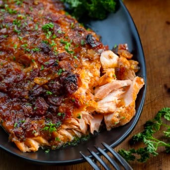 Close up of flakey Bacon Jam Salmon on a black platter.