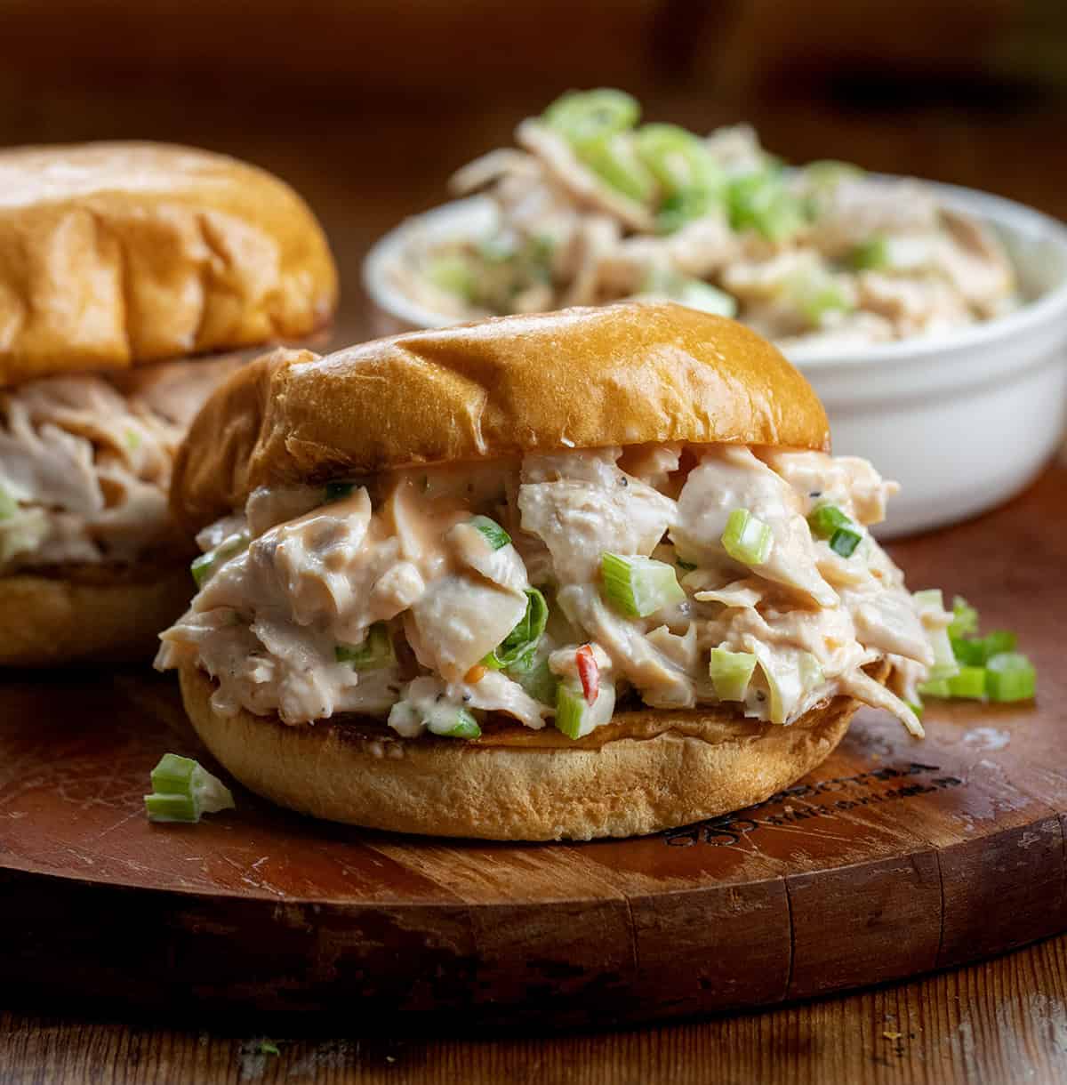 This Bang Bang Chicken Salad is creamy, slightly spicy, and ready in just minutes, perfect for a quick lunch, light dinner, or game-day spread! Bang Bang Chicken Salad sandwiches on a wooden cutting board.