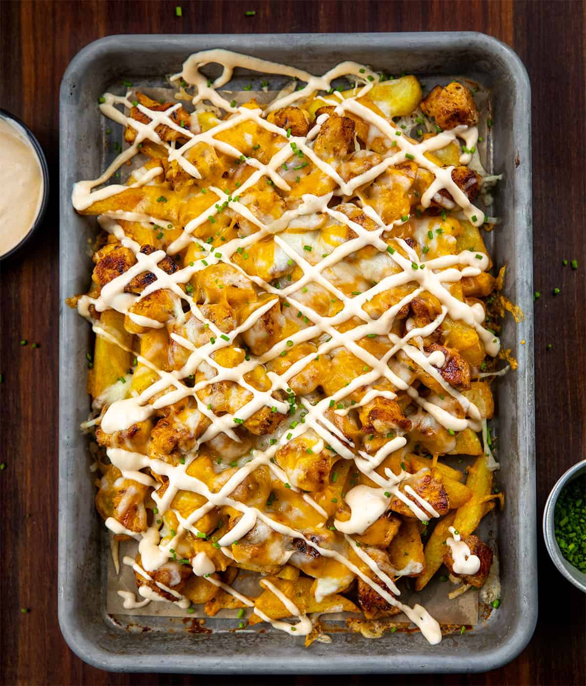 Discover the bold flavors of Cajun Chicken Loaded Fries, perfect for game day or family gatherings. Enjoy crispy, cheesy goodness! Pan of Cajun Chicken Loaded Fries on a wooden table from overhead.