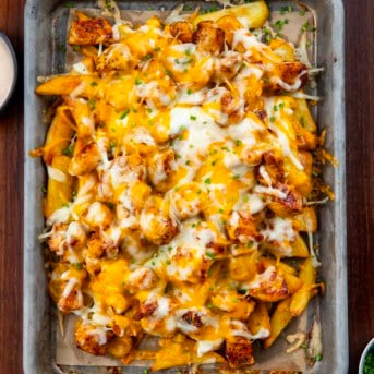 Pan of Cajun Chicken Loaded Fries on a wooden table from overhead.