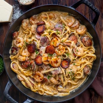 Skillet of Cajun Shrimp and Sausage Pasta on a wooden table from overhead.