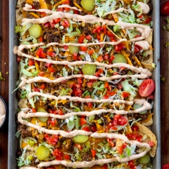 Sheet pan of Cheeseburger Nachos on a wooden table from overhead.