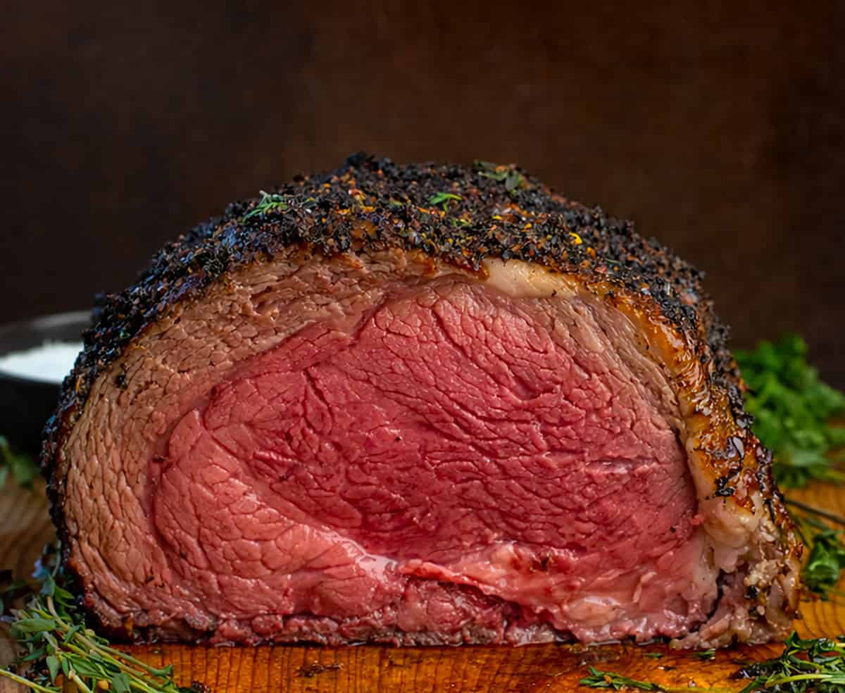 All the flavor of my popular Prime Rib gets an extra punch with my homemade Cowboy Butter! This prime rib is perfectly roasted, with a golden, flavorful crust, and each juicy slice is topped with a spicy, herby butter that melts into the meat! Sliced into Cowboy Butter Prime Rib showing a medium-rare meat.