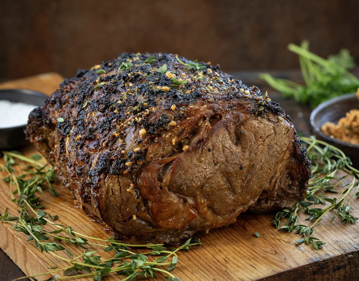 All the flavor of my popular Prime Rib gets an extra punch with my homemade Cowboy Butter! This prime rib is perfectly roasted, with a golden, flavorful crust, and each juicy slice is topped with a spicy, herby butter that melts into the meat! Whole Cowboy Butter Prime Rib on a wooden cutting board.