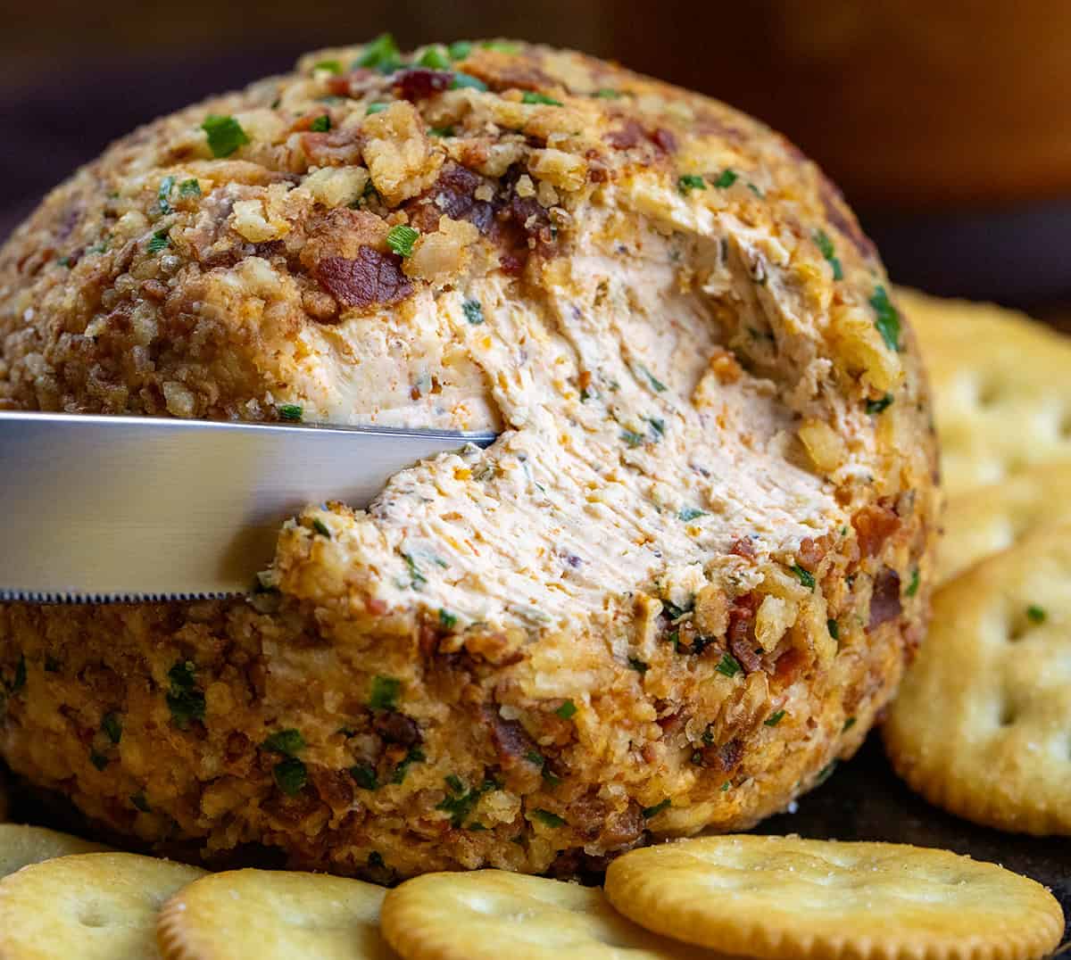 This Cowboy Cream Cheese Ball is bold, flavorful, and a guaranteed crowd-pleaser. It’s based on my classic Cowboy Cream Cheese, with pepperjack cheese, spices, and a hint of heat, topped with crispy bacon, and crunchy French’s onions! Using a knife to take a portion of a Cowboy Cream Cheese Ball.