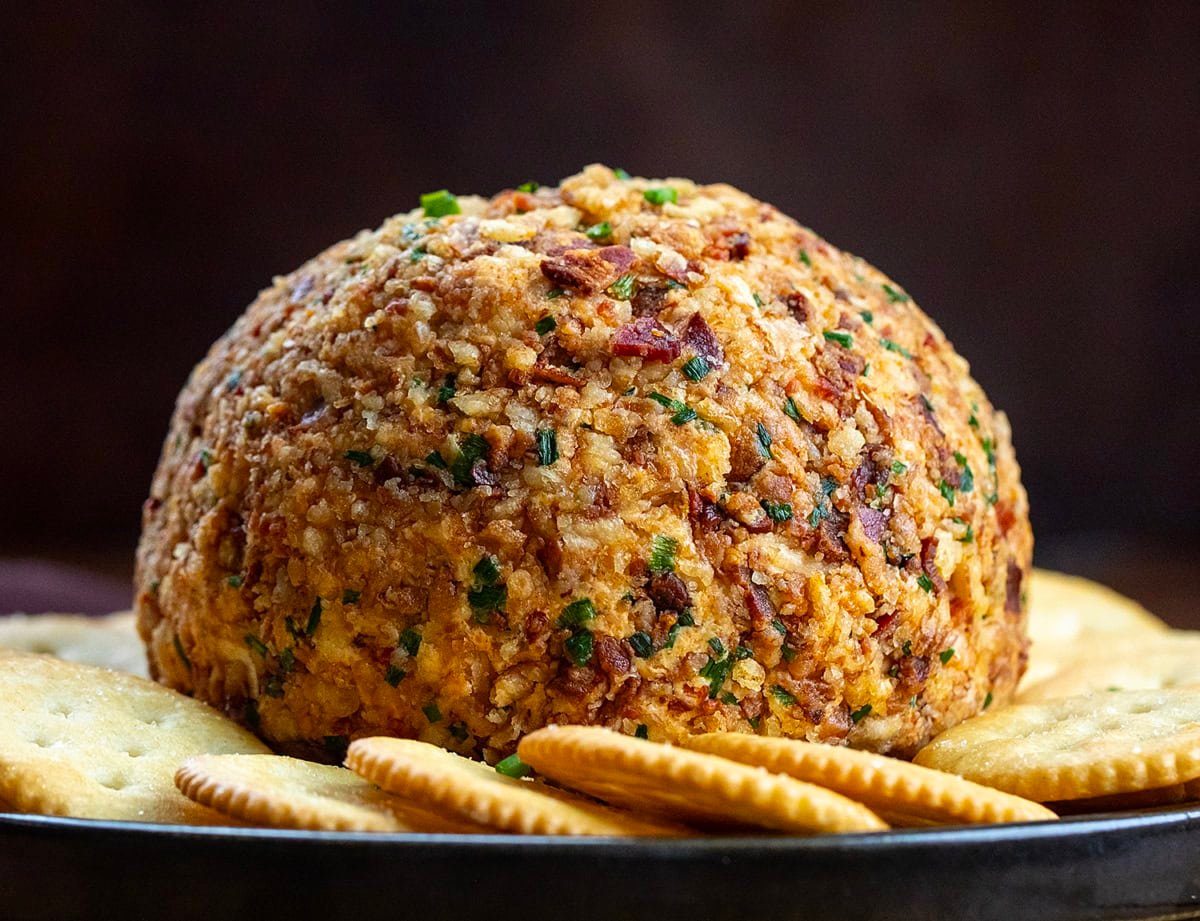 This Cowboy Cream Cheese Ball is bold, flavorful, and a guaranteed crowd-pleaser. It’s based on my classic Cowboy Cream Cheese, with pepperjack cheese, spices, and a hint of heat, topped with crispy bacon, and crunchy French’s onions! Whole Cowboy Cream Cheese Ball on a black plate surrounded by crackers.