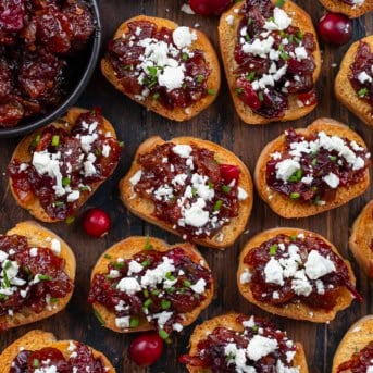 Cranberry Bacon Jam and Feta Crostini laid out on a wooden table from overhead.
