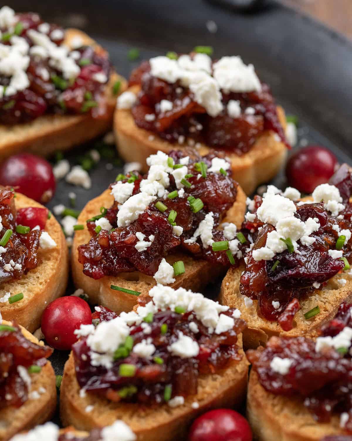 These Cranberry Bacon Jam and Feta Crostini are the ultimate sweet-and-savory appetizer! Crisp, golden baguette slices are topped with my homemade cranberry bacon jam and a sprinkle of creamy feta! Close up of Cranberry Bacon Jam and Feta Crostini.